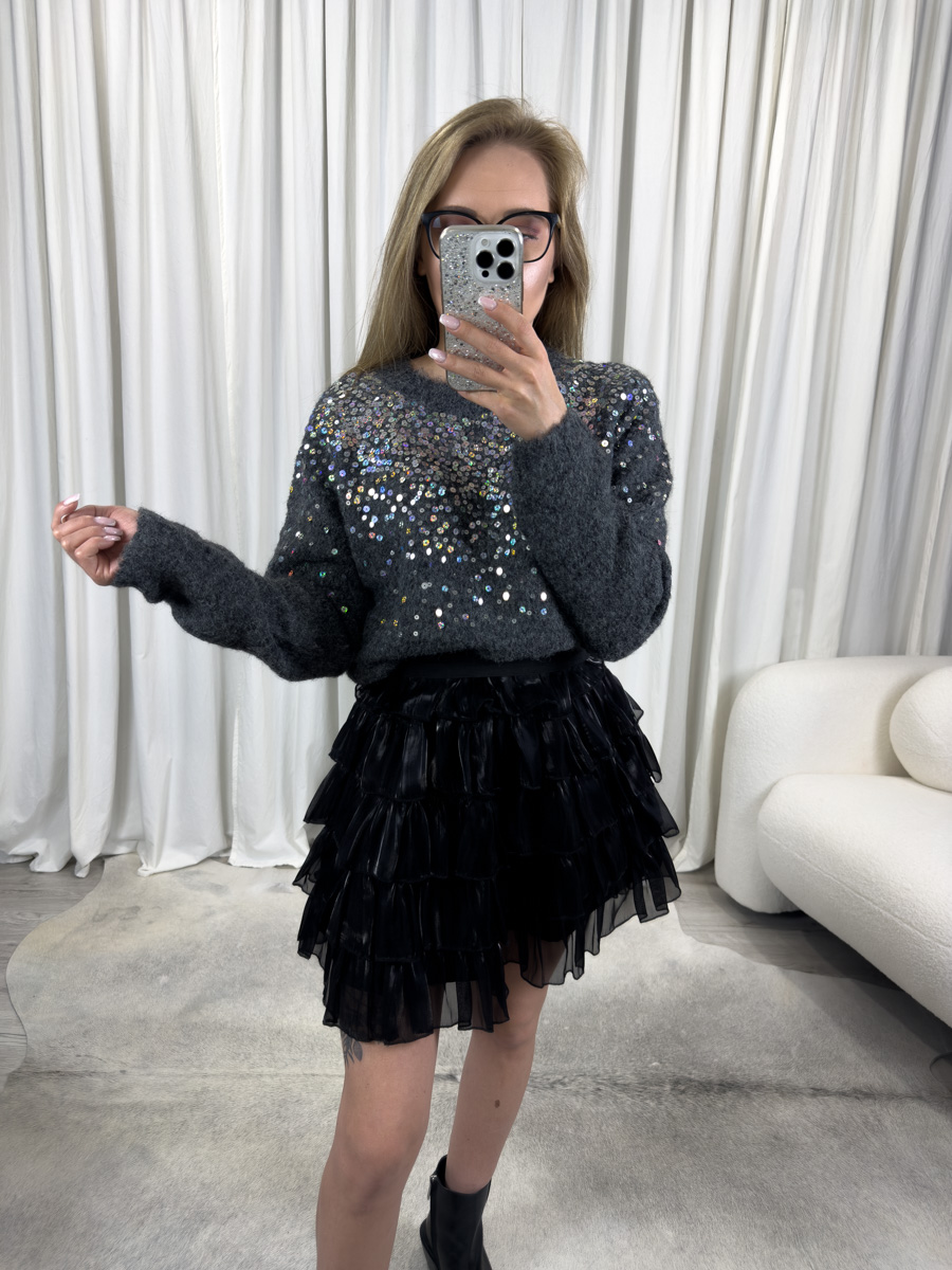 IMG_5818 Sweter Sequins ciemny szary z okrągłym dekoltem, błyszczącymi cekinami i klasycznym fasonem, zestawiony z czarną spódnicą mini z falbanami – elegancka stylizacja na zimowy wieczór.