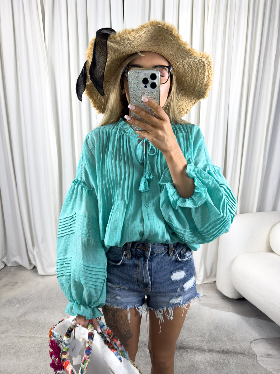 koszula-boho-turkusowa-wiya-4 Zdjęcie produktowe sklepu internetowego z odzieżą damską – modelka ubrana w koszule Boho w kolorze turkusowym marki Wiya, jeansowe szorty oraz dodatki typu słomiany kapelusz, wiklinowa torebka koszyk