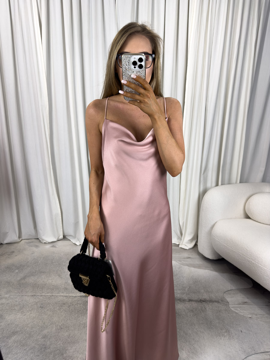 sukienka-maxi-satynowa-goldie-pudrowy-roz Modelka w sukience maxi satynowej Goldie na cienkich ramiączkach z dekoltem typu woda, długa kreacja w kolorze pudrowego różu - zdjęcie produktowe do sklepu internetowego z odzieżą damską.